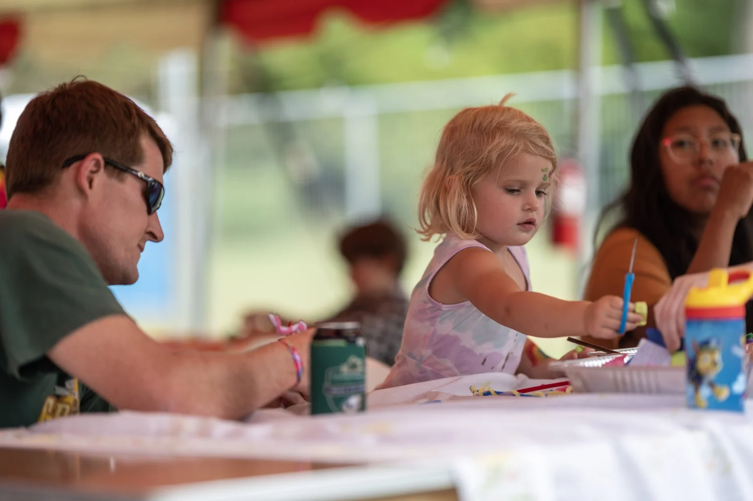 A face painted kid blowing bubbles beside the first Kids Zone sign at Touch of Brews 2021