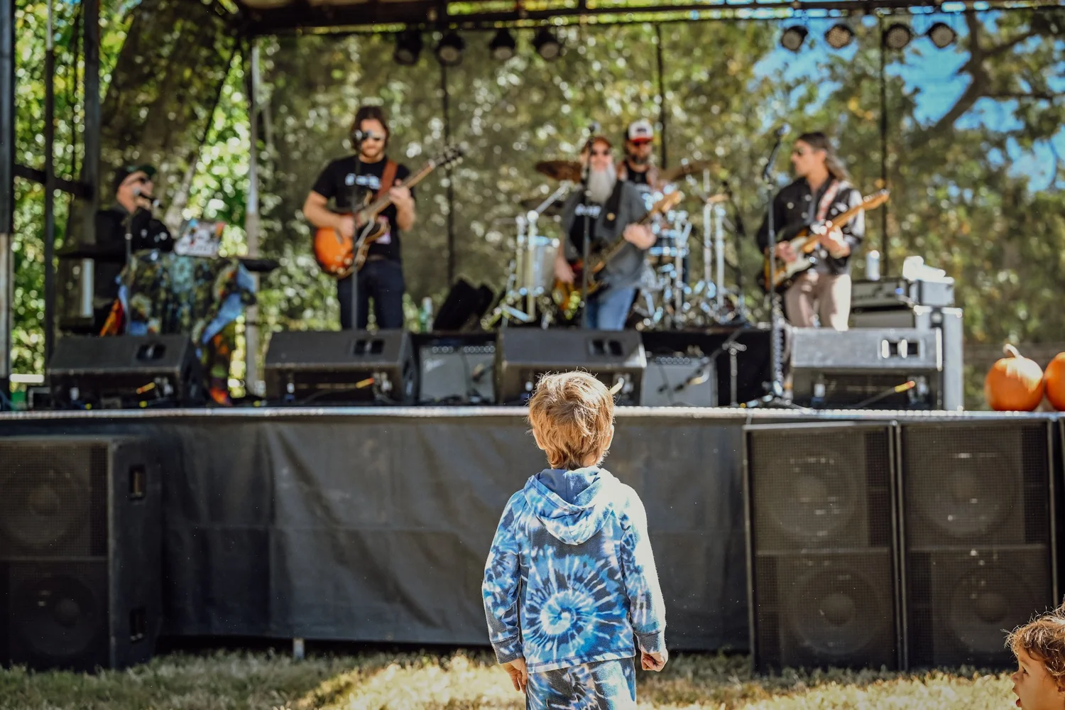 A toddler in tie dye watching the band at Touch of Brews 2022