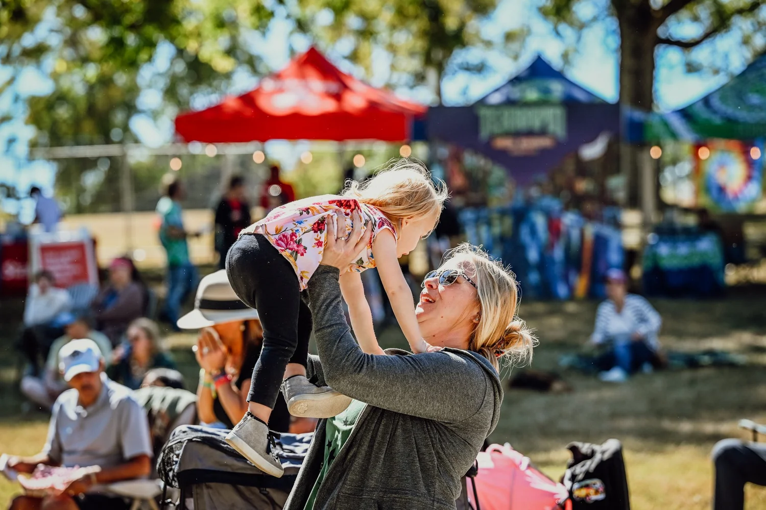 A mom lifting her daughter in the October sun at Touch of Brews 2022
