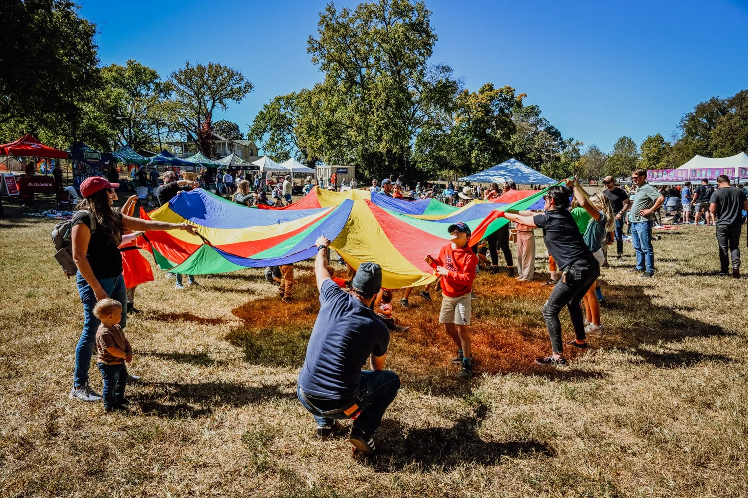 Families playing the parachute game at the expanded Touch of Brews 2022 Kids Zone
