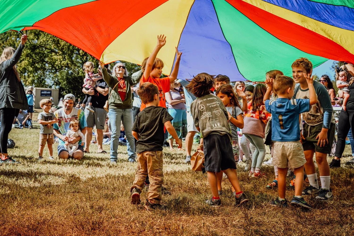 Kids playing under the rainbow parachute at the Touch of Brews 2022 Kids Zone