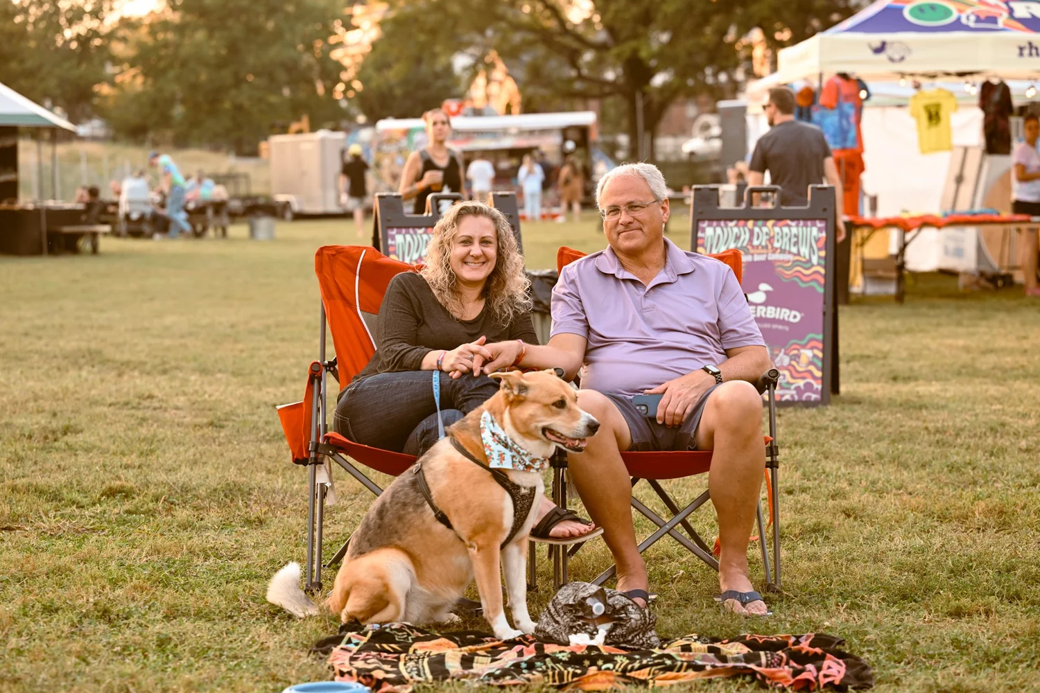 A leashed dog in a bandana with festival goers beside the Touch of Brews sign in Nashville